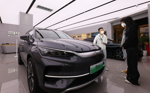 比亞迪店內(nèi)，一名銷售人員（左）正在向兩位顧客介紹車輛信息。深圳特區(qū)報記者 楊浩翰 攝