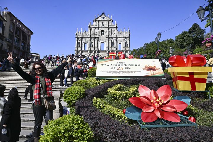游客在澳門大三巴牌坊慶祝布景旁留影（2024年12月18日攝）。新華社記者 程一恒 攝