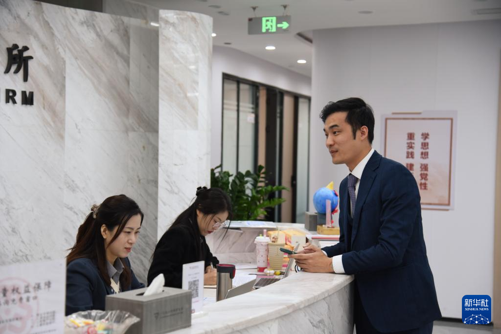 澳門律師阮嘉銳（右）在和同事交談（12月19日攝）。新華社記者 洪澤華 攝