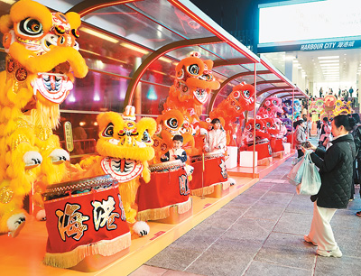 近日在香港維多利亞港畔，游客和醒獅合影。新華社記者 褚萌萌攝