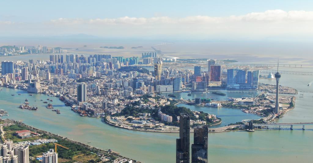 從珠海市區(qū)拍攝的澳門及遠(yuǎn)處的港珠澳大橋（2024年11月26日攝，無(wú)人機(jī)照片）。新華社記者 鄧華 攝